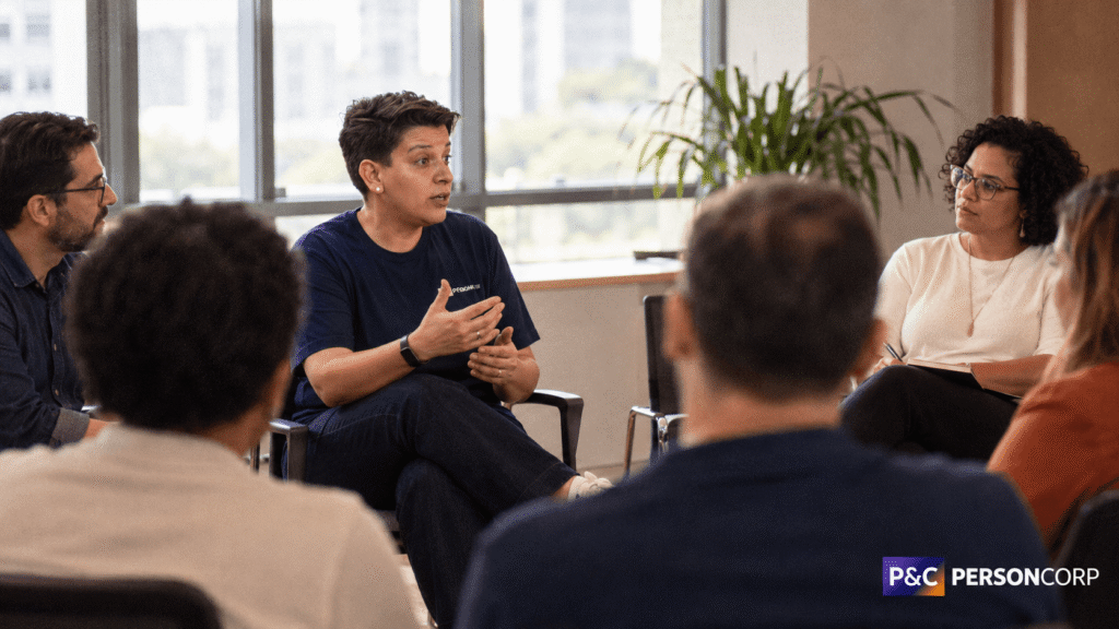Luciana Régis conduz uma roda de conversa sobre comunicação não violenta com profissionais em uma sala de treinamento